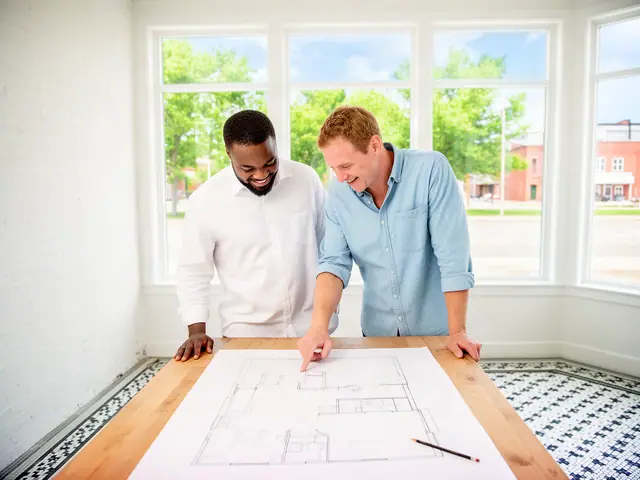 Two business partners looking over a pencil floor sketch in an empty storefront.